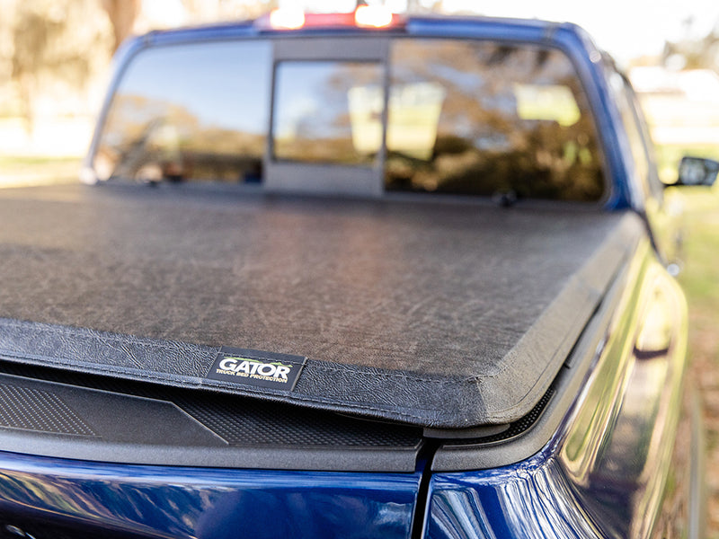 Gator SFX soft tri-fold tonneau cover: closed on a blue pickup, rear view with the Gator badge