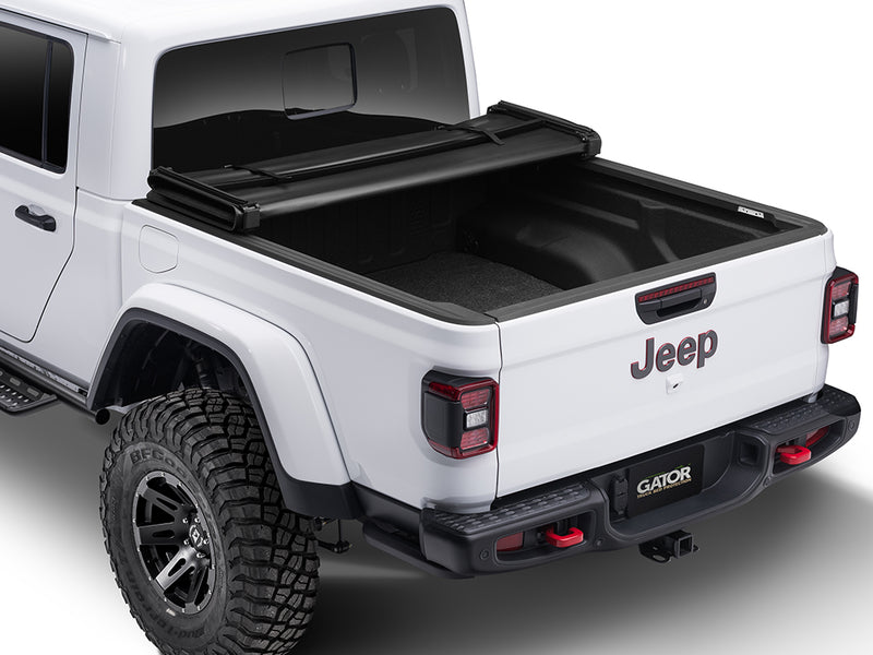 Gator SFX soft tri-fold tonneau cover: folded fully forward on a white Jeep pickup