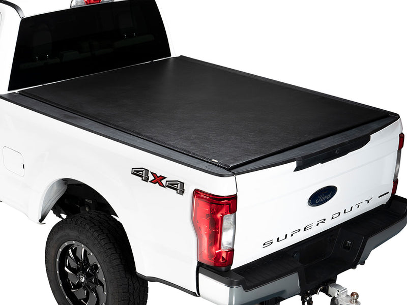 Gator SRX soft roll-up tonneau cover: A white Ford Super Duty pickup with a black soft roll-up tonneau cover closed over the bed, seen from the rear quarter