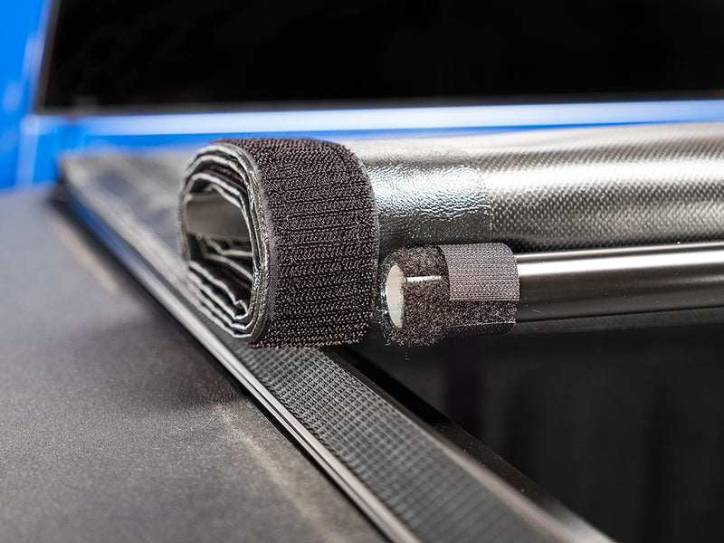 Gator SRX soft roll-up tonneau cover: Close-up of a rolled-up soft vinyl tonneau cover held by a hook-and-loop strap at the front of a truck bed