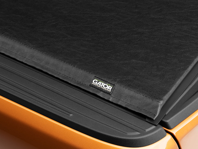 Close-up of the Gator SRX tonneau cover: corner of a black soft tonneau cover with the Gator label over an orange bed rail