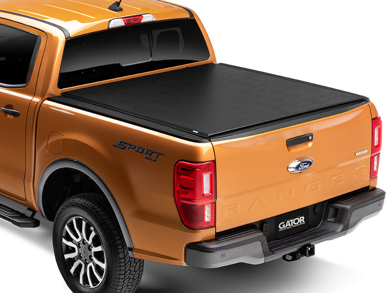 Gator SRX soft roll-up tonneau cover: Orange midsize pickup, rear three-quarter view, with a black soft roll-up tonneau cover closed over the bed