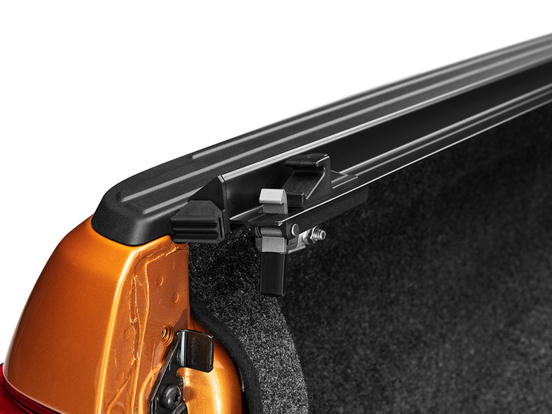 Gator SRX soft roll-up tonneau cover: Tailgate end of a tonneau side rail with a clamp on an orange bed wall over a carpet liner