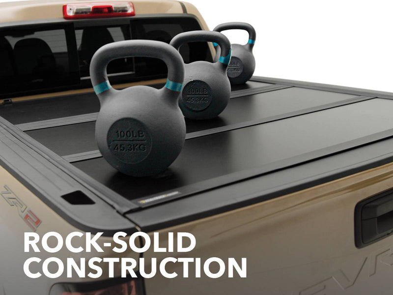 Three kettlebells resting on a closed Gator EFX cover on a tan Chevrolet Colorado, captioned Rock-solid construction