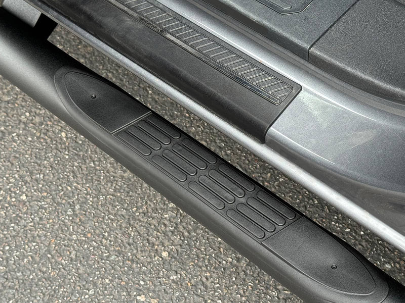 Go Rhino 4000 Series: close-up of a black molded step pad on a round side step below a gray rocker panel