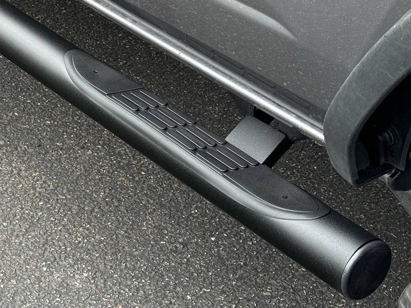 Go Rhino 4000 Series: close-up of a black round side step end cap, step pad and mounting bracket below a gray body