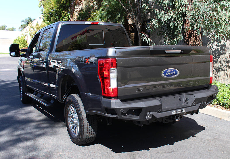 Go Rhino BR20.5: black rear bumper with Go Rhino tag installed on a gray Ford Super Duty crew cab, rear three-quarter view (shown with running boards, not included)