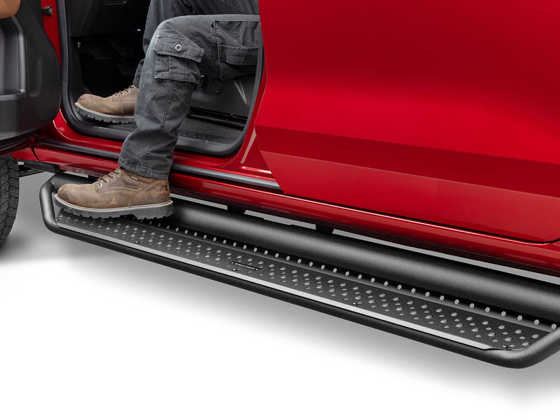 Go Rhino Dominator D1: person in cargo pants and work boots stepping onto a black perforated side step under the open door of a red truck