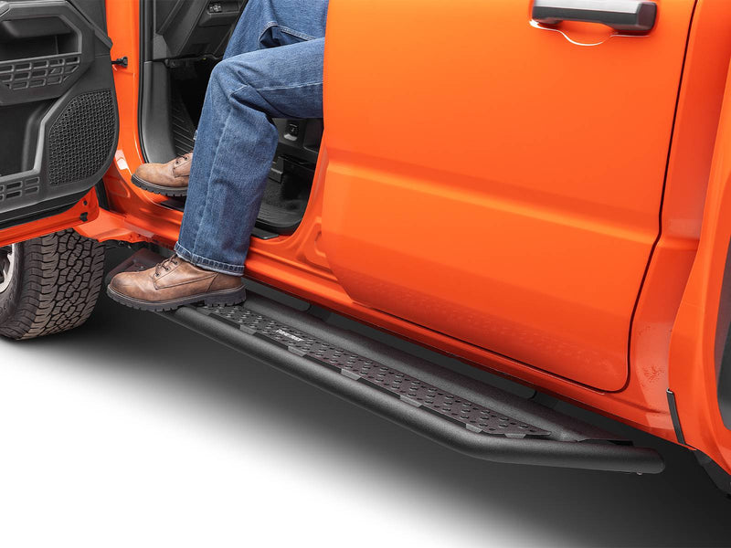 Go Rhino Dominator D6: person in jeans and work boots stepping onto a black side step under the open front door of an orange truck