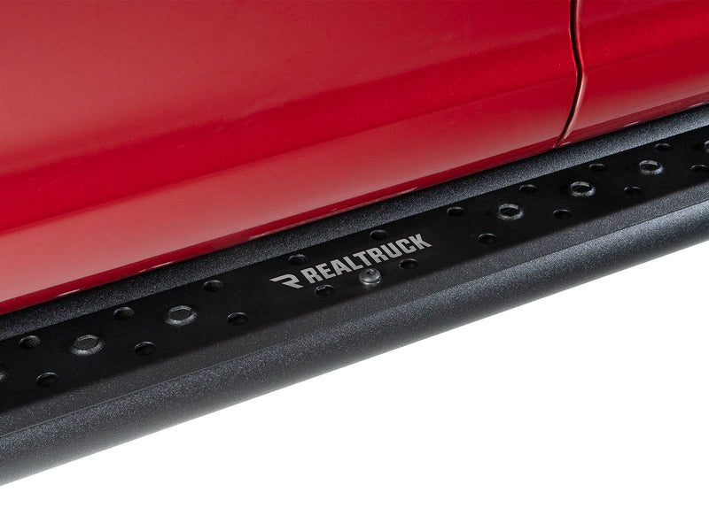 Go Rhino Dominator DSS: close-up of a black slider board with RealTruck badge plate mounted under a red door