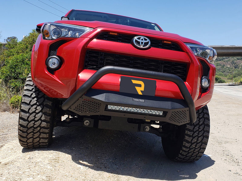 Go Rhino RC4 LR: red SUV front view low angle with a textured black bull bar and LED light bar across the lower opening (shown with LED light bar, aftermarket tires and lift, not included)