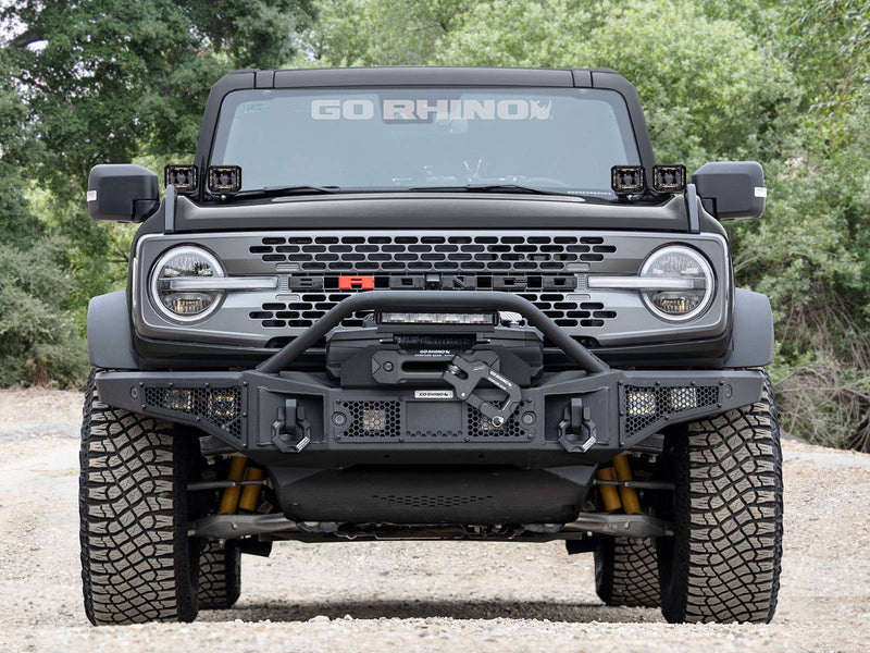Go Rhino Rockline: gray SUV head-on with a textured black full-width winch bumper and overrider hoop (shown with winch, cube lights in bumper, A-pillar cube lights, LED light bar, not included)