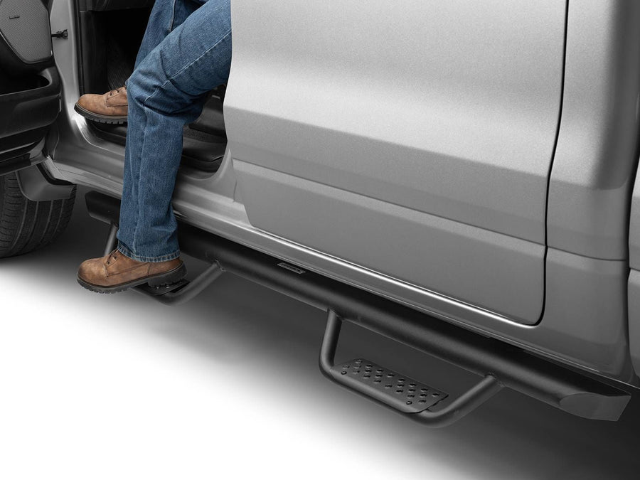 Go Rhino Dominator Xtreme D2 Side Steps: Person in jeans and work boots stepping on a black drop step below an open silver truck door