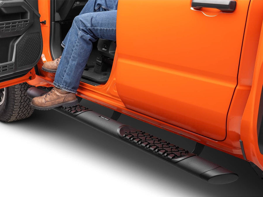 Go Rhino V-Series V3 Side Steps: Person in jeans and work boots stepping on a black side step to enter an orange pickup