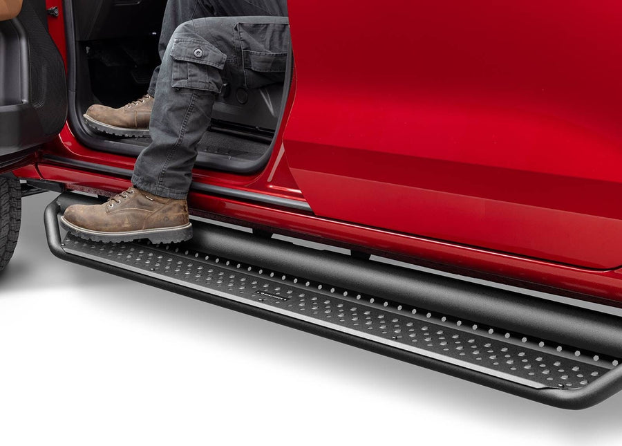 Go Rhino Dominator D1 Side Steps: Person in cargo pants and work boots stepping onto a black perforated side step under the open door of a red truck