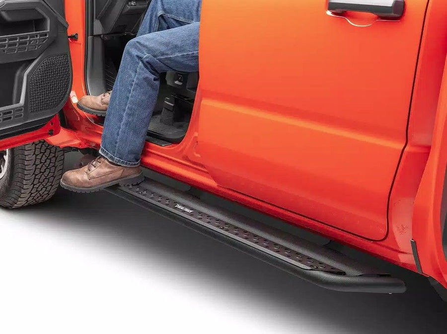 Go Rhino Dominator DSS Sliders: Person in jeans and boots stepping onto a black perforated slider step under an open orange door