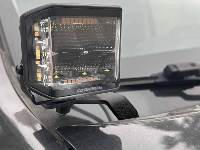 Go Rhino XE: close-up of a GO RHINO cube light on a black hood bracket at the hood edge by the windshield (shown with LED cube light, not included)
