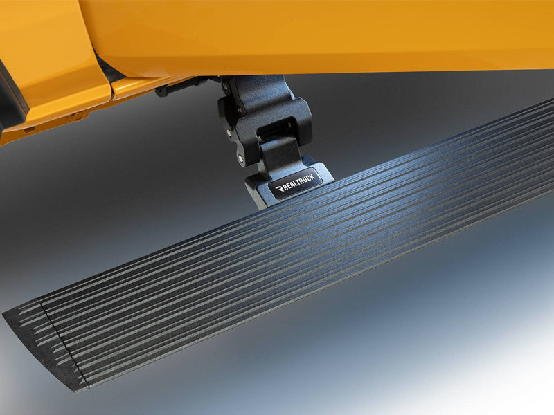 Textured black power running board deployed with its LED step light glowing under a yellow body