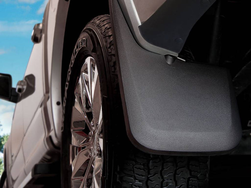 Husky Liners Custom Molded: black molded mud guard behind the front wheel of a silver pickup with chrome wheels