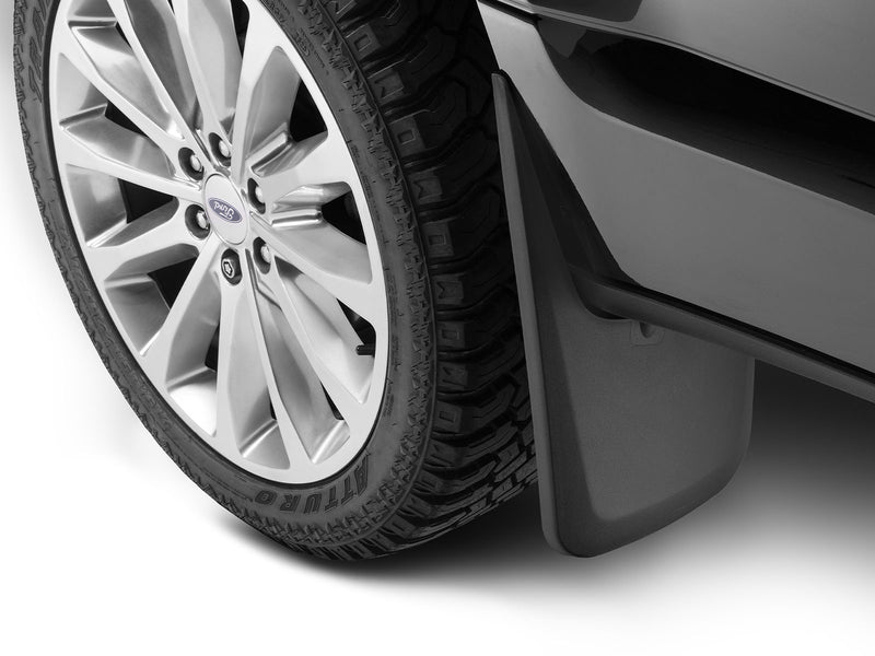 Husky Liners Custom Molded: black mud guard installed behind the front wheel of a black Ford pickup