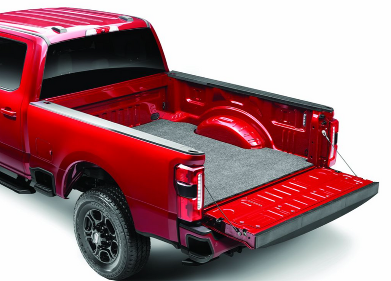 Husky Liners Guardian Comfort: gray carpet bed mat installed in the bed of a red full-size pickup with the tailgate lowered, shown in a Ford F-250/F-350 Super Duty bed