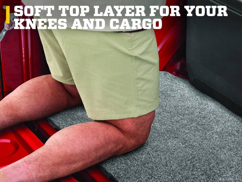 Husky Liners Guardian Comfort: person in khaki shorts kneeling on a gray carpet bed mat in a red pickup bed