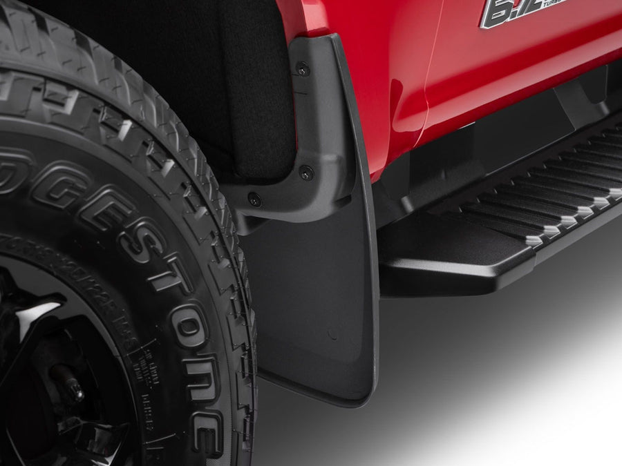 Husky Liners Custom Molded Mud Guards: Black molded mud guard installed behind the front wheel of a red Ford Super Duty with a 6.7L badge on the fender