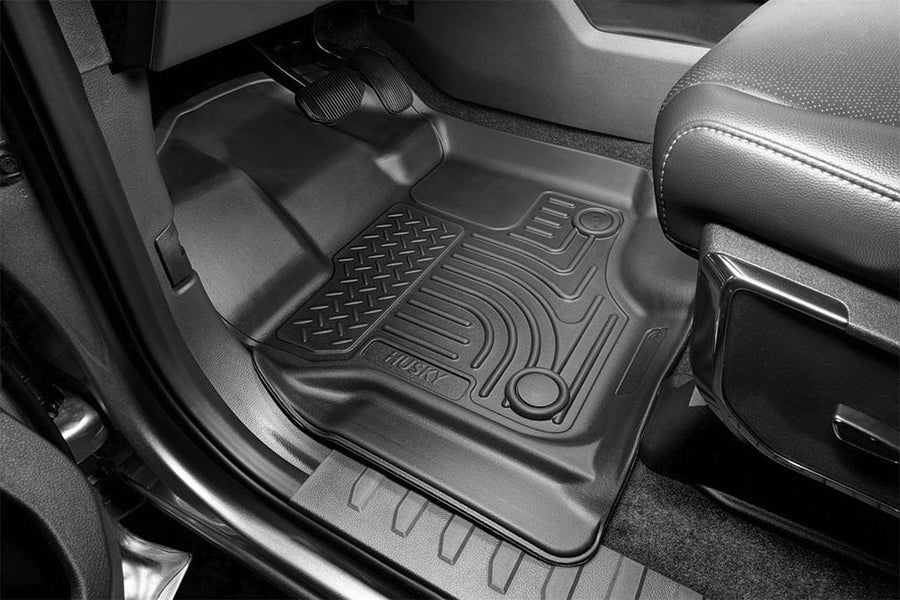 Husky Liners WeatherBeater Floor Liners: Black floor liner with curved channels and diamond-plate pad installed on the driver side of a truck below the pedals