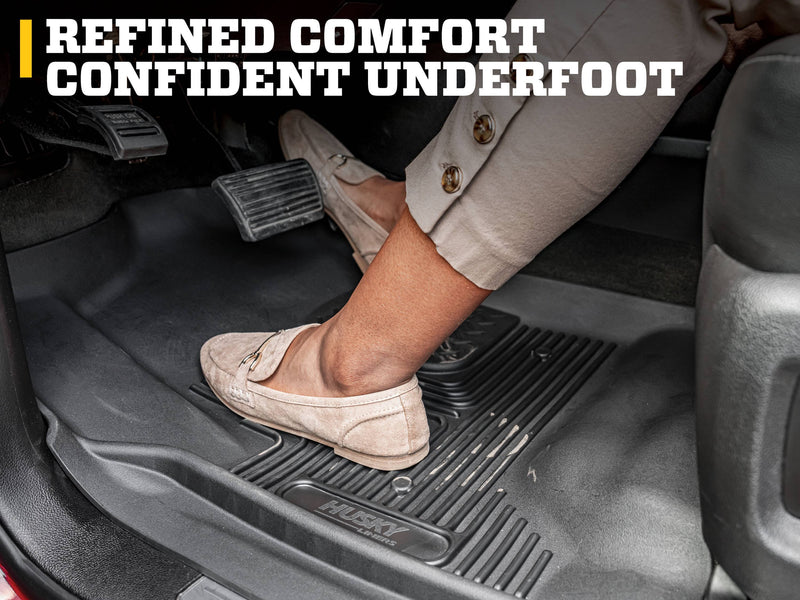 Husky Liners X-act Contour: foot in a beige loafer on the pedal over a black Husky floor liner in a driver footwell