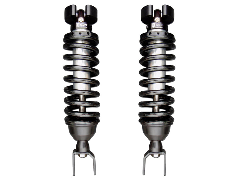ICON Vehicle Dynamics 2.5 Series Coilover Kit: a pair of ICON 2.5 VS coilovers with black springs, top hats and fork lower mounts standing side by side on white