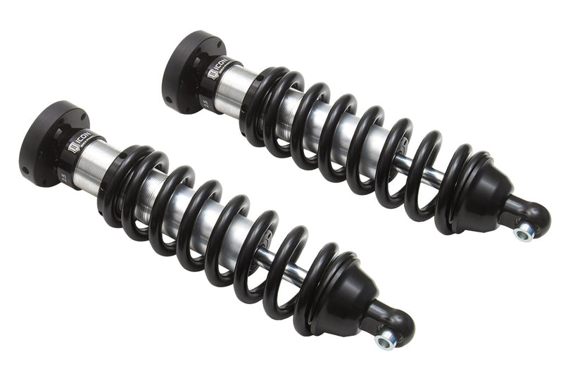 ICON Vehicle Dynamics 2.5 Series Coilover Kit: a pair of ICON 2.5 VS front coilovers with black springs and top hats laid diagonally side by side on white