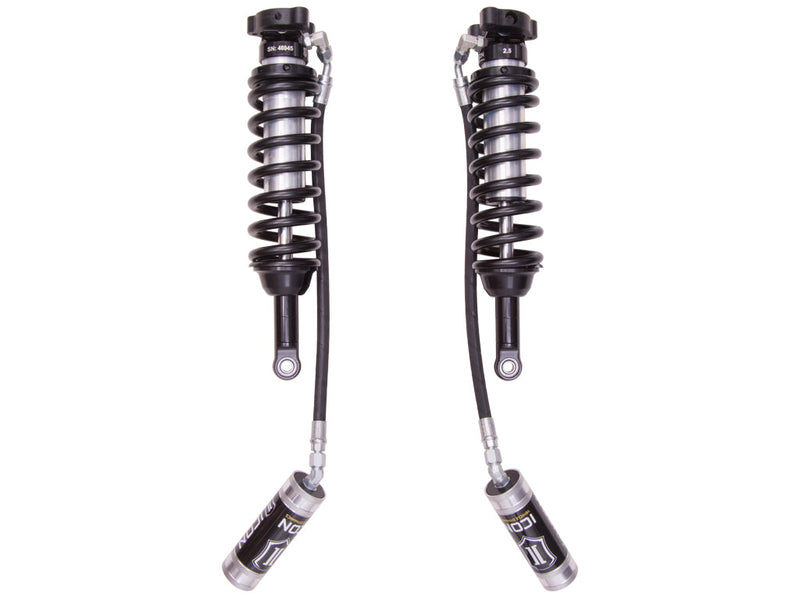 ICON Vehicle Dynamics 2.5 Series Coilover Kit: a pair of ICON 2.5 VS remote-reservoir coilovers with black springs and silver ICON reservoirs hanging low on long hoses, on white