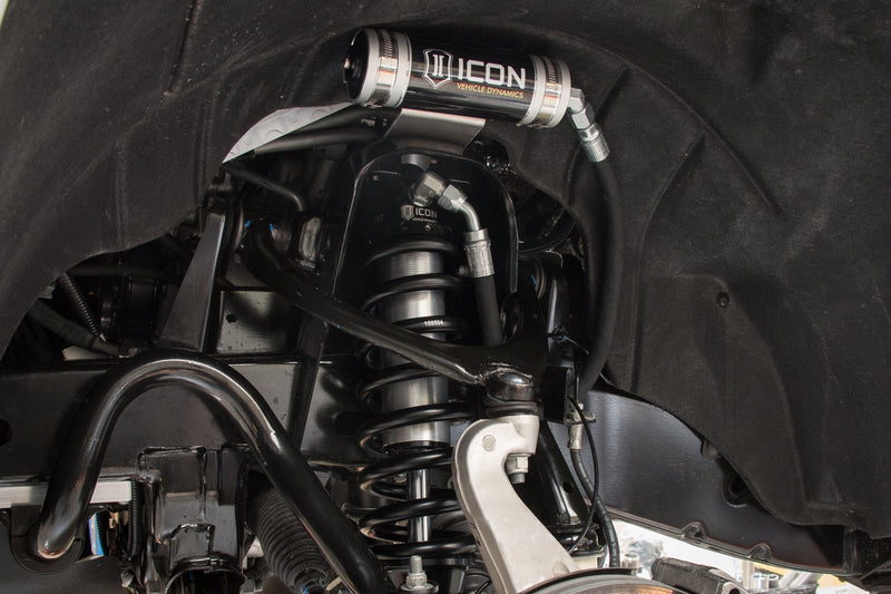 ICON Vehicle Dynamics 2.5 Series Coilover Kit on a vehicle: installed ICON 2.5 remote-reservoir coilover with black spring in a truck front suspension, silver ICON reservoir mounted above in the wheel well