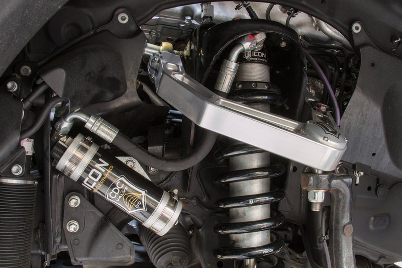ICON Vehicle Dynamics 2.5 Series Coilover Kit on a vehicle: installed ICON 2.5 remote-reservoir coilover with silver CDC Valve reservoir and black spring under a silver ICON billet upper control arm