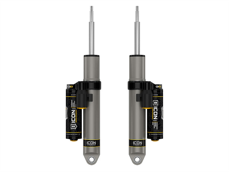 ICON Vehicle Dynamics 2.5 Series Shock Absorbers: rendered pair of gray ICON 2.5 aluminum series shocks with CDEV piggyback reservoirs and stem tops, standing on white