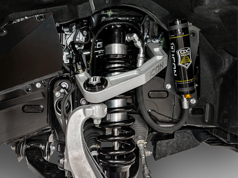 ICON Vehicle Dynamics 3.0 Series Coilover on a vehicle: installed ICON 3.0 remote-reservoir coilover with black spring under a silver ICON billet upper control arm, CDC Valve reservoir mounted in the wheel well