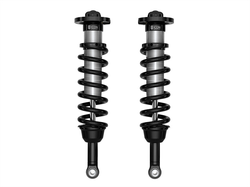 A pair of ICON 2.5 VS front coilovers with black springs, black top hats and extended lower mounts standing side by side on white.