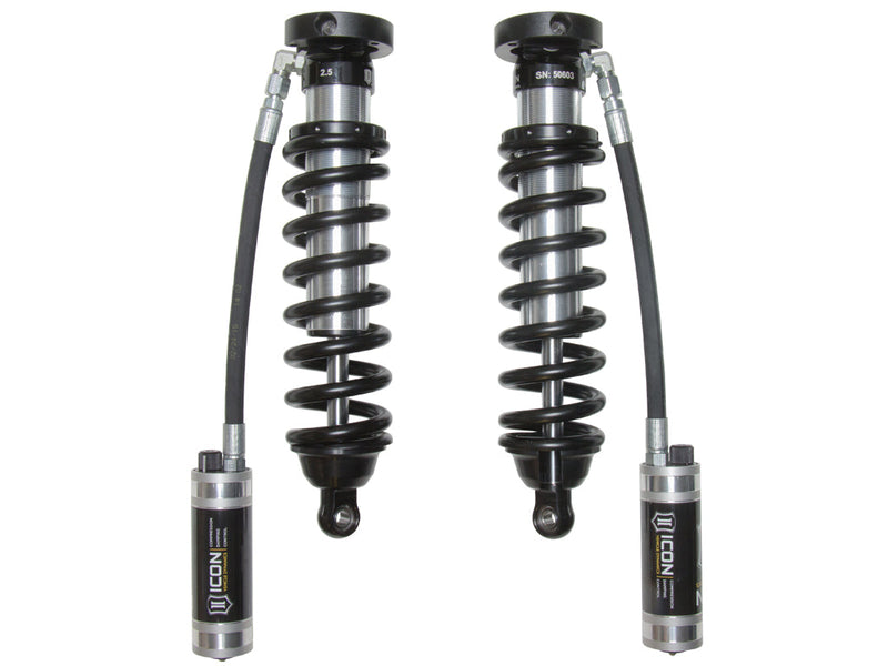 A pair of ICON 2.5 VS remote-reservoir coilovers with black springs and CDC-adjustable ICON reservoirs hanging on hoses, on white.