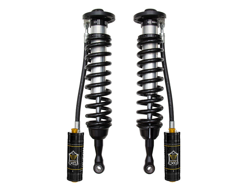 A pair of ICON 2.5 VS remote-reservoir coilovers with black springs and black CDC Valve reservoirs hanging on hoses, on white.