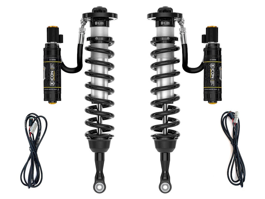 A pair of ICON 2.5 VS remote-reservoir coilovers with black springs, electronic-valve reservoirs and two wiring harnesses, on white.
