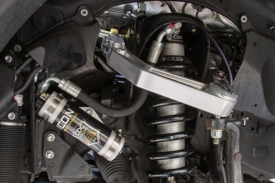 Installed ICON 2.5 remote-reservoir coilover with silver CDC Valve reservoir and black spring under a silver ICON billet upper control arm.