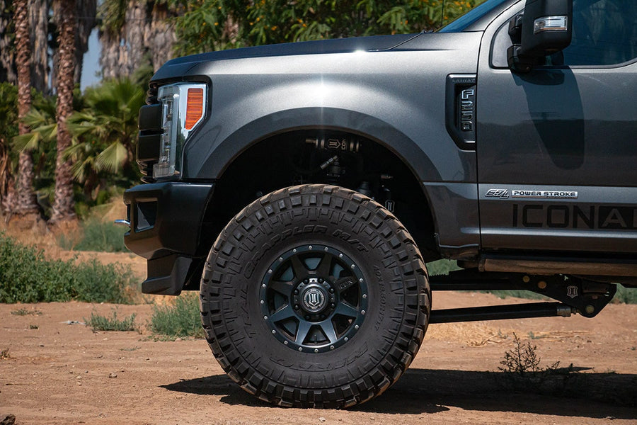 Front wheel and fender of a gray lifted Ford F-250 Super Duty with an ICON coilover visible in the wheel well.