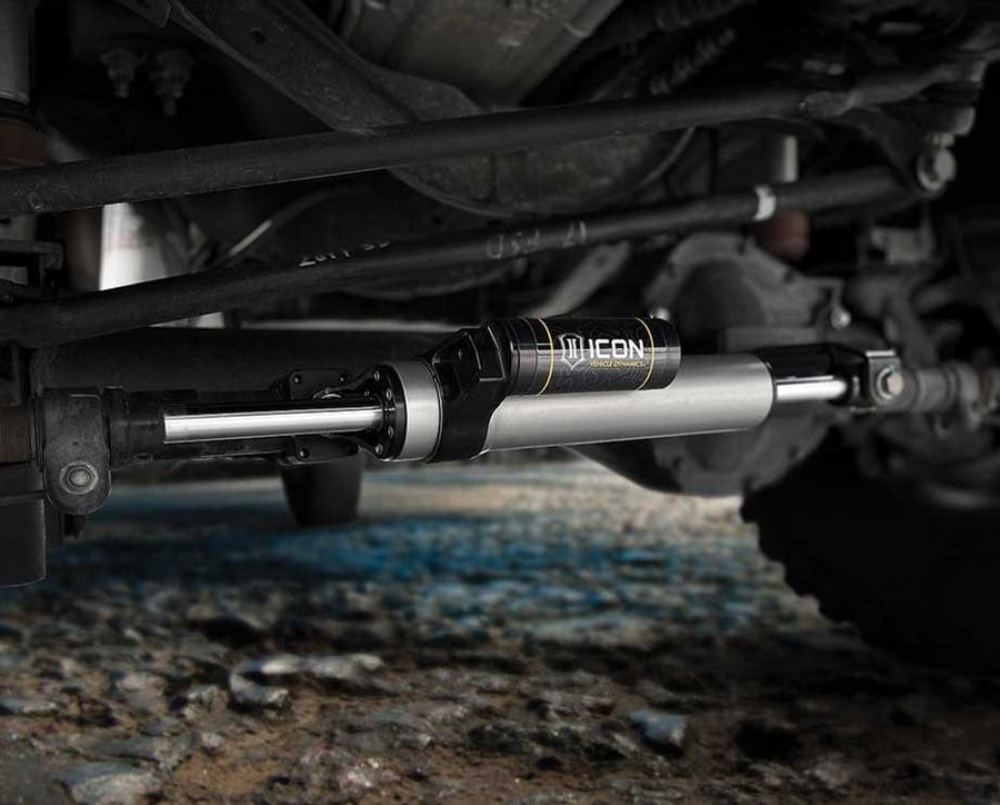 ICON through-shaft steering stabilizer installed on a solid front axle tie rod, low angle over gravel.