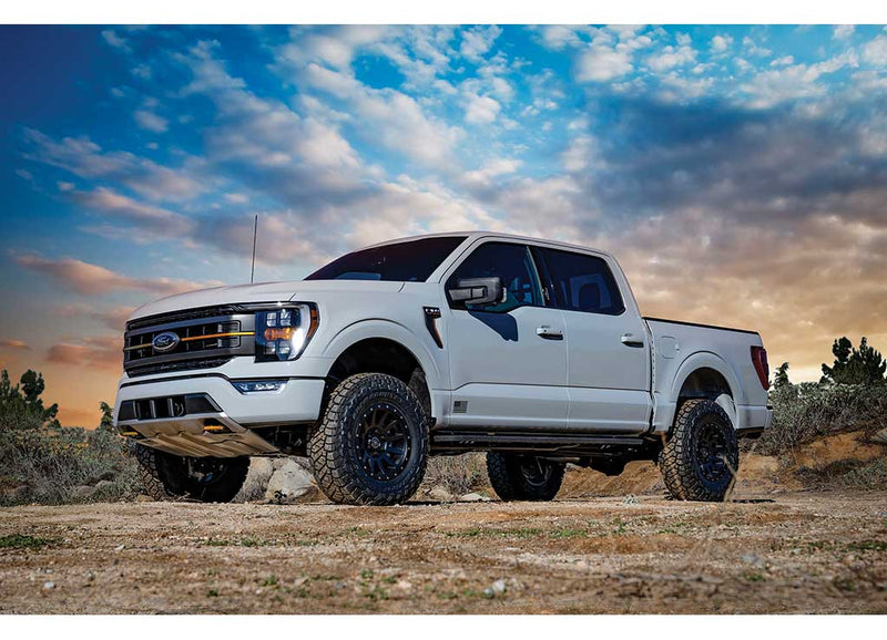 ICON Vehicle Dynamics Stage Suspension System installed on a Ford F-150, front three-quarter view: front three-quarter of a lifted white Ford F-150 crew cab at sunset, Ford grille badge visible