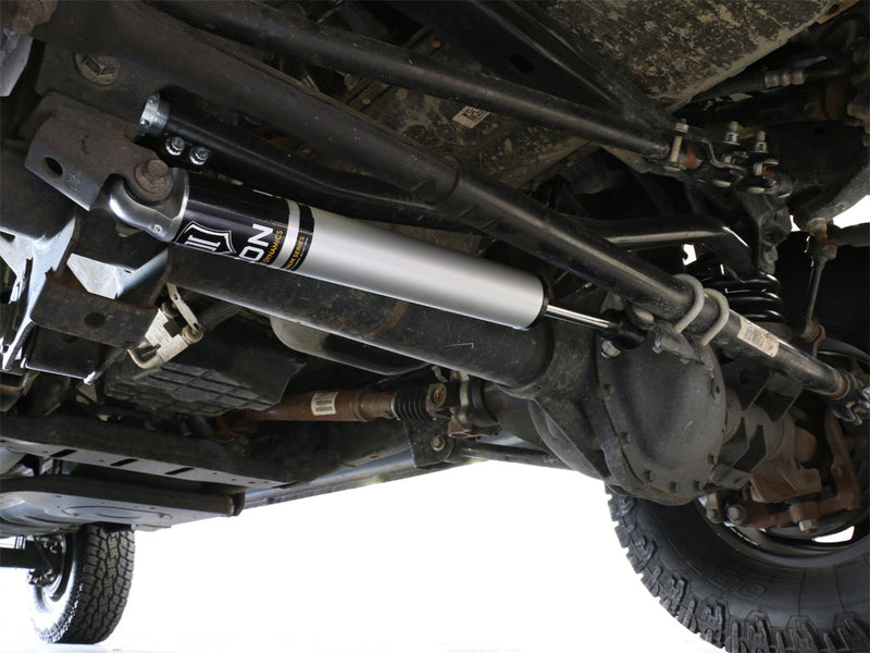 ICON Vehicle Dynamics Ultimate Front End Kit on a vehicle: underside view of an ICON steering stabilizer installed along the tie rod on a truck's solid front axle