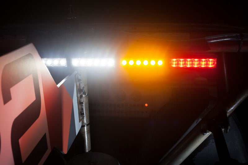 KC HiLiTES 28" Multi-Function Rear-Facing Chase LED Light Bar on a vehicle: close-up of a rear light bar lit white, amber and red on a roll cage