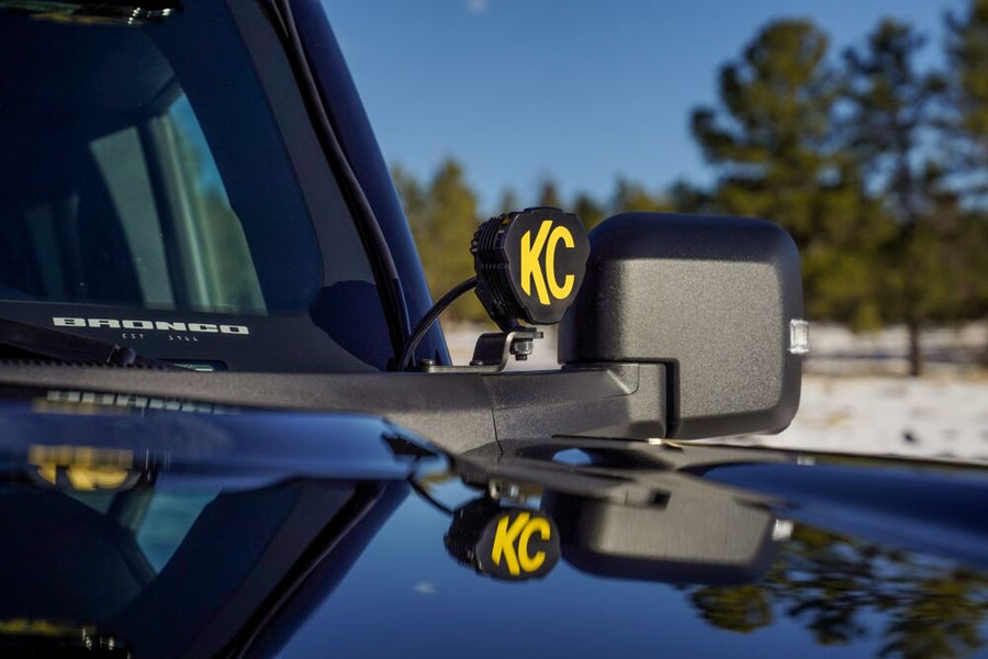 KC HiLiTES A-Pillar Ditch Light Mount Brackets on a Ford Bronco: ditch light bracket mounted by the mirror of a blue Ford Bronco holding a small KC light