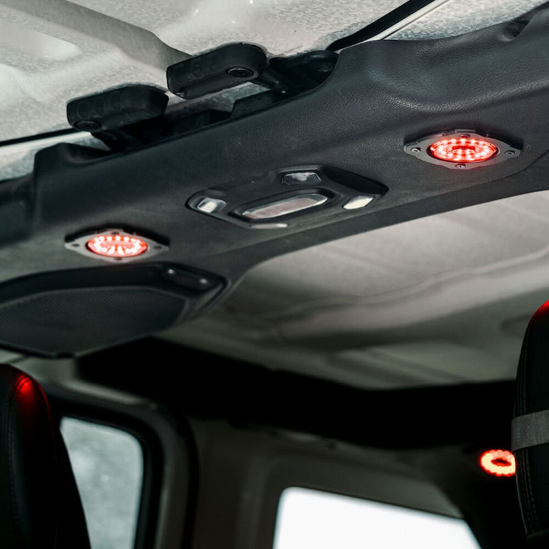 KC HiLiTES Cyclone V2 LED Mount Adapter on a Jeep Wrangler JL: Jeep interior roof sound bar with two round lights glowing red set into flush mounts beside the dome light