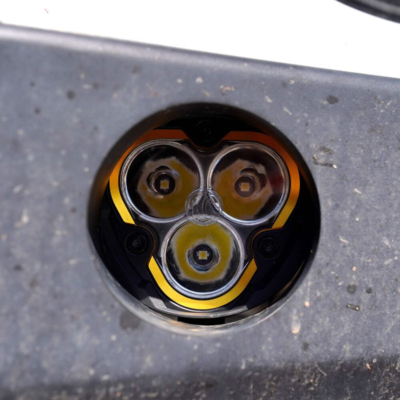 KC HiLiTES FLEX ERA 3 Universal Shroud Pair on a vehicle: round three-LED light with amber trim set into a round hole in a gray steel bumper