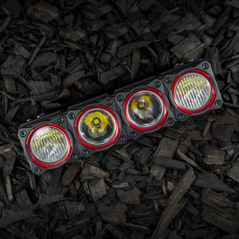 KC HiLiTES FLEX ERA LED Light Bar 10" Segment Bezel Kit on a vehicle: FLEX ERA 10" LED light bar segment fitted with four red bezel rings, lying on dark wood mulch